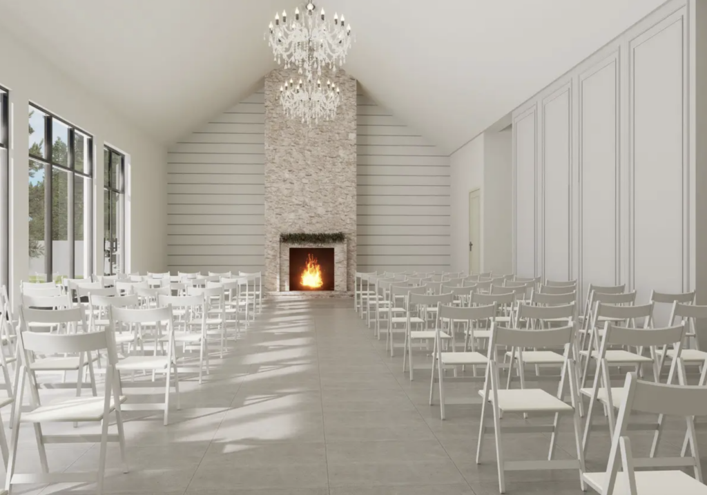 An all-white wedding ceremony space with a brick fireplace, white walls, and white chairs.